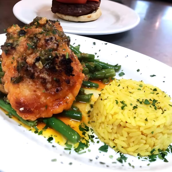Angelina's Trattoria's salmon with green beans and yellow rice, garnished with parsley.